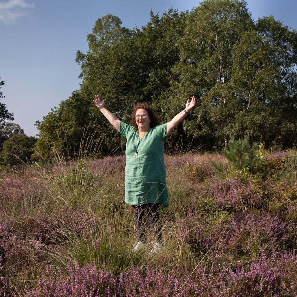 Vrouw met gespreide armen op de heide na herstel van een burn-out