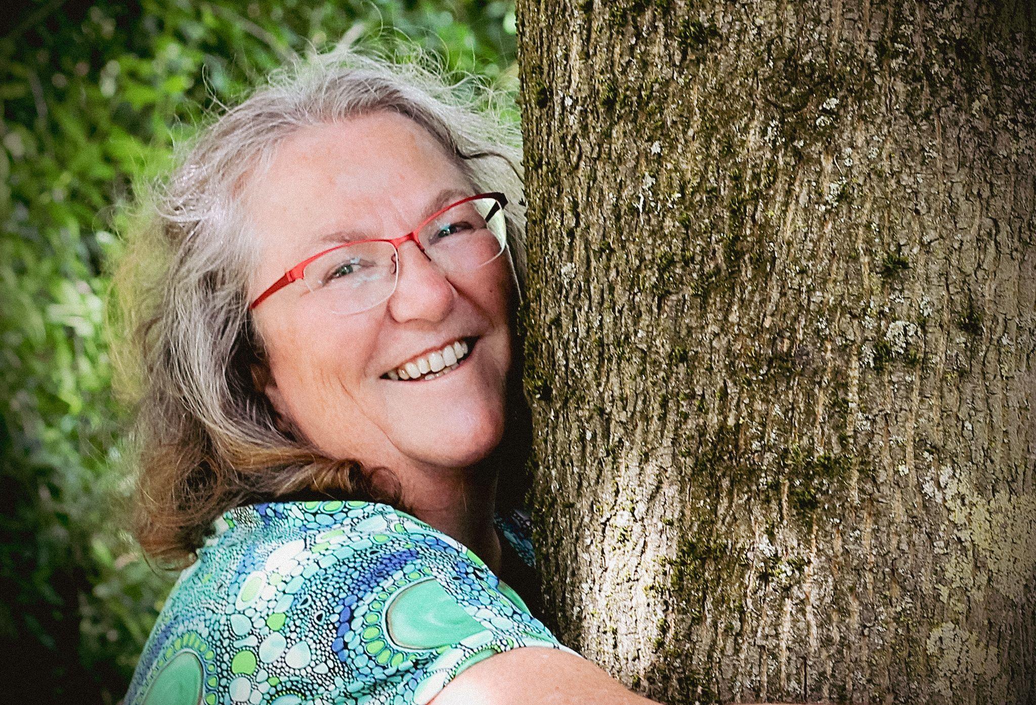 Vrouw omarmt een boom tijdens een sessie in de natuur